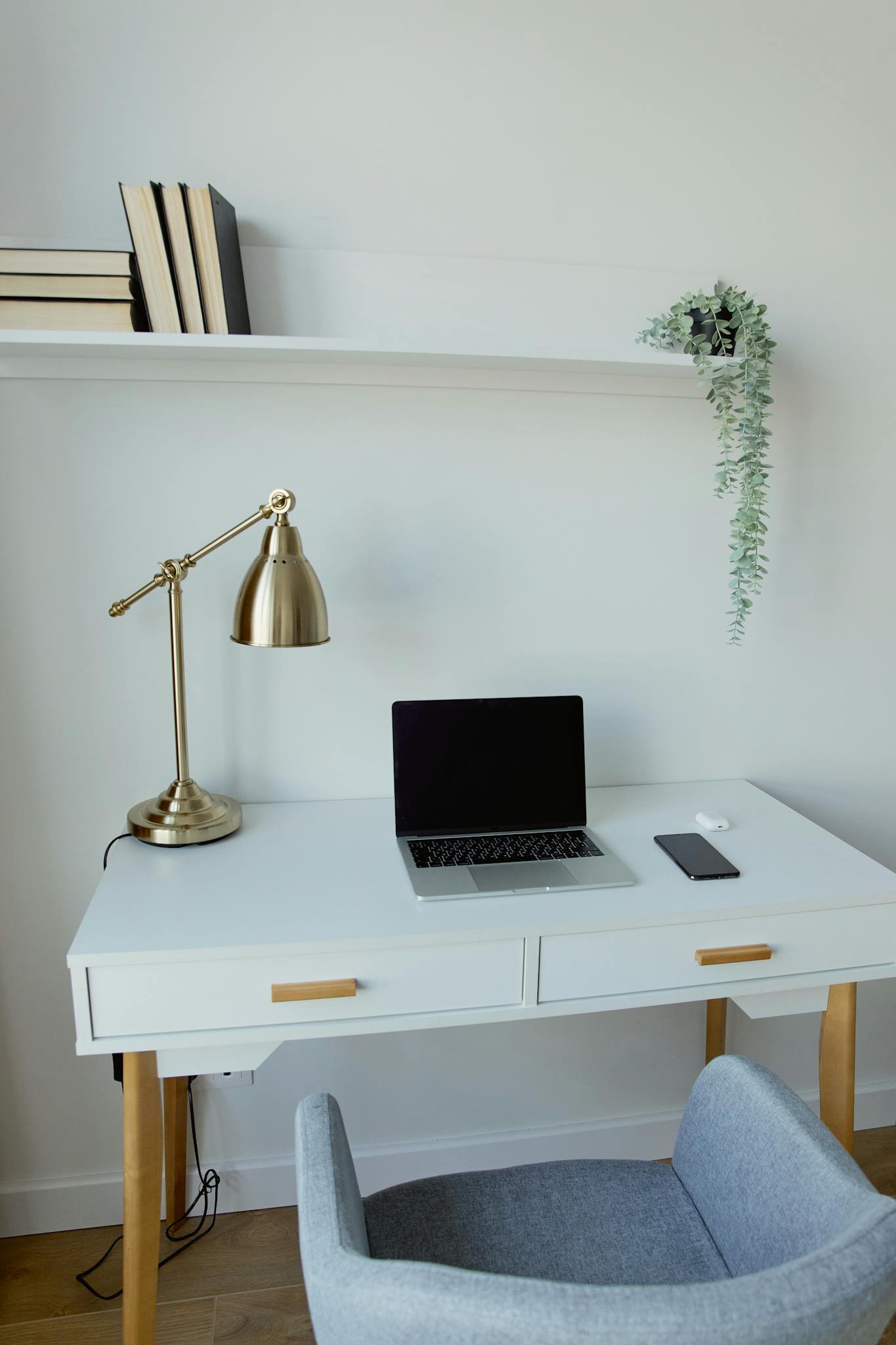 A clean, minimalist home office setup with a laptop, lamp, and modern desk.